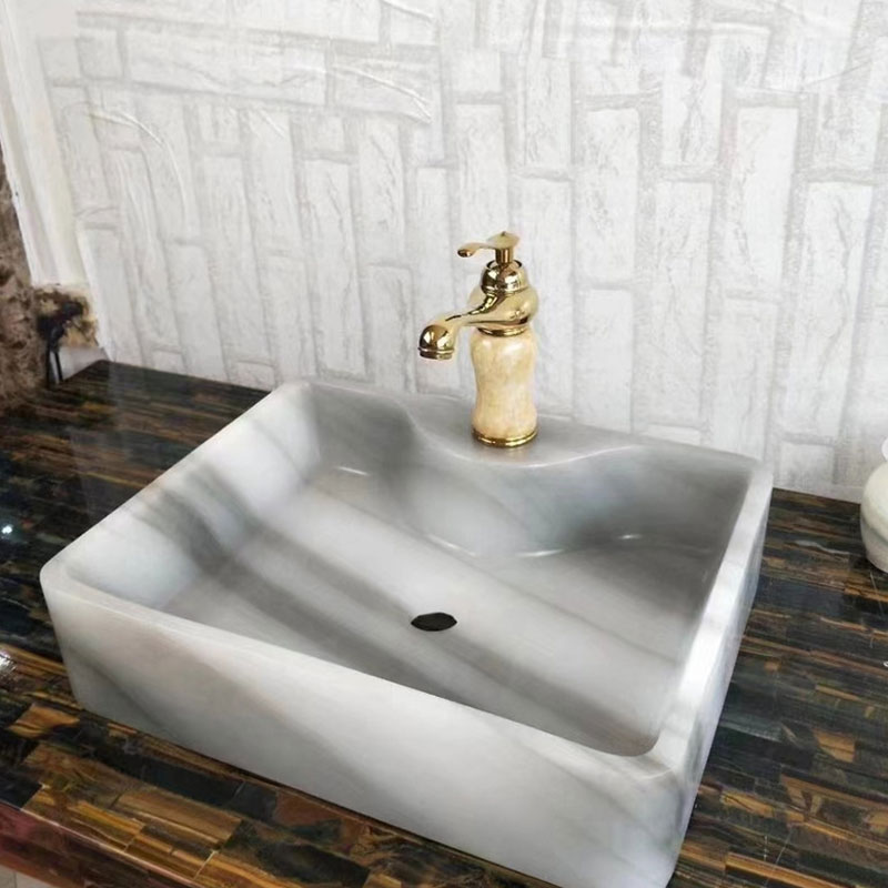 La dalle blanche de marbre de Calacatta Jade surmonte le lavabo transparent