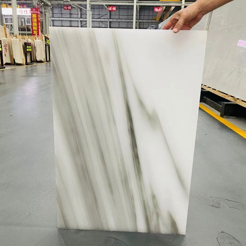 La dalle blanche de marbre de Calacatta Jade surmonte le lavabo transparent