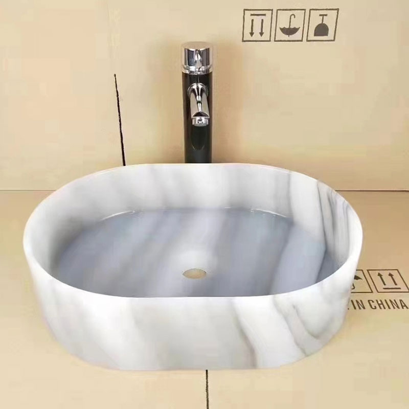 La dalle blanche de marbre de Calacatta Jade surmonte le lavabo transparent